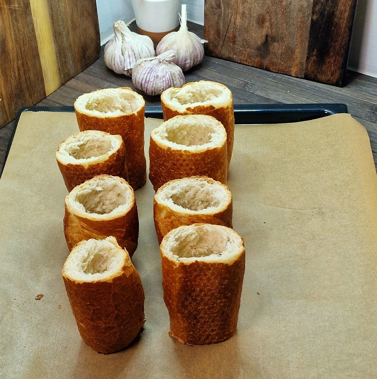 Składniki na kominy chlebowe z kiełbasą podwawelską, pieczarkami, cebulą i serem, przygotowane na desce do krojenia